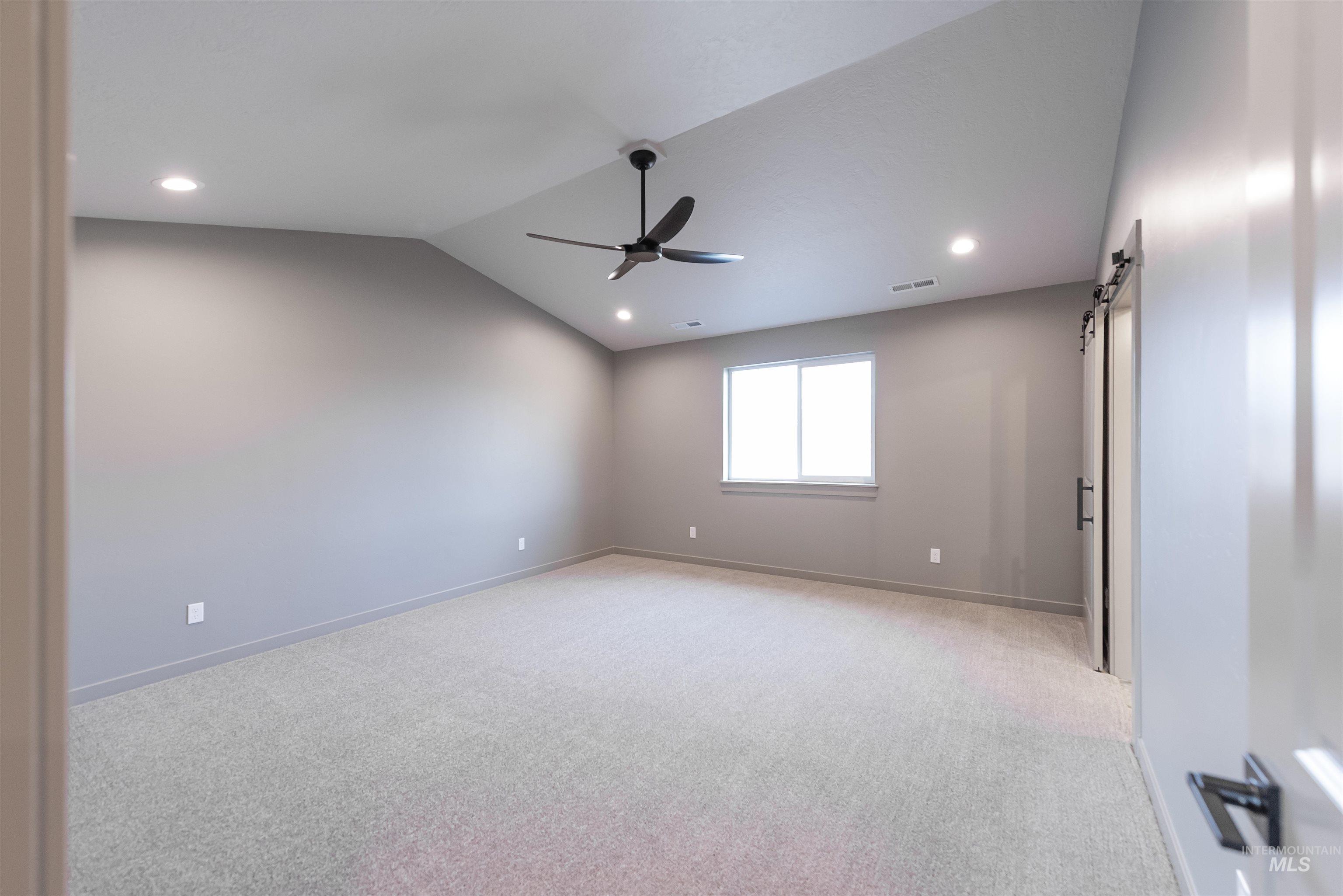 360 South Bumper Way Boise, ID 83716 - Photo 15 of 34 Empty room featuring a barn door, vaulted ceiling, light colored carpet, recessed lighting, and ceiling fan