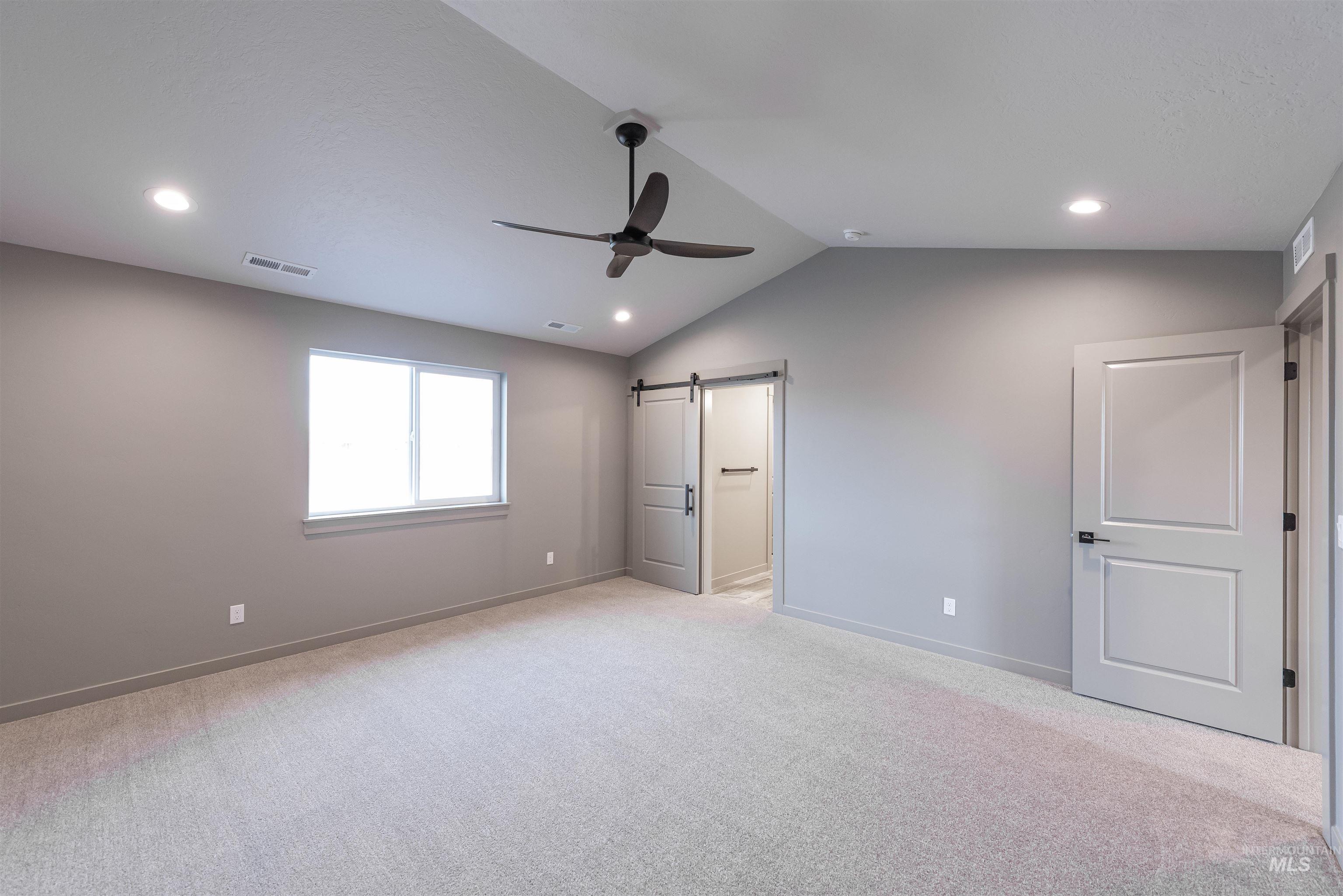 360 South Bumper Way Boise, ID 83716 - Photo 16 of 34 Unfurnished bedroom featuring a barn door, lofted ceiling, light carpet, a ceiling fan, and recessed lighting