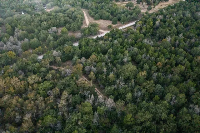 an aerial view of residential house with outdoor space and trees all around