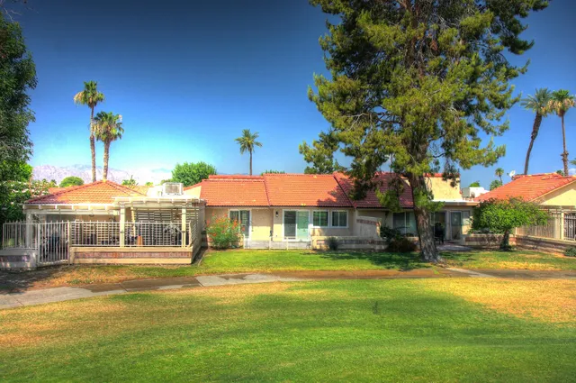 a view of a swimming pool with a yard and palm trees