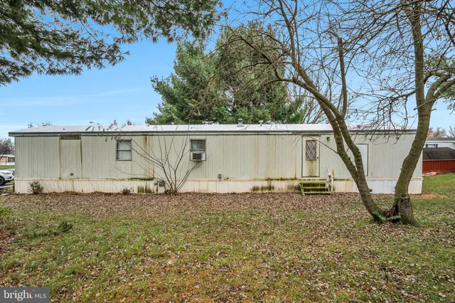 a backyard of a house with large trees and wooden fence