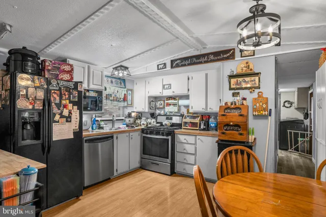 a kitchen with stainless steel appliances granite countertop a sink dishwasher and a refrigerator with wooden floor