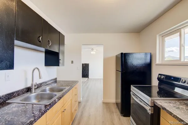 a kitchen with granite countertop a refrigerator stove and sink