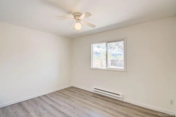 an empty room with wooden floor chandelier fan and windows