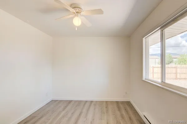 an empty room with a window and a fan