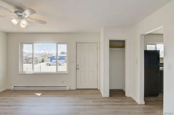 an empty room with wooden floor and a ceiling fan