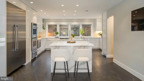 a kitchen with stainless steel appliances granite countertop a stove top oven a sink a dining table and chairs with wooden floor