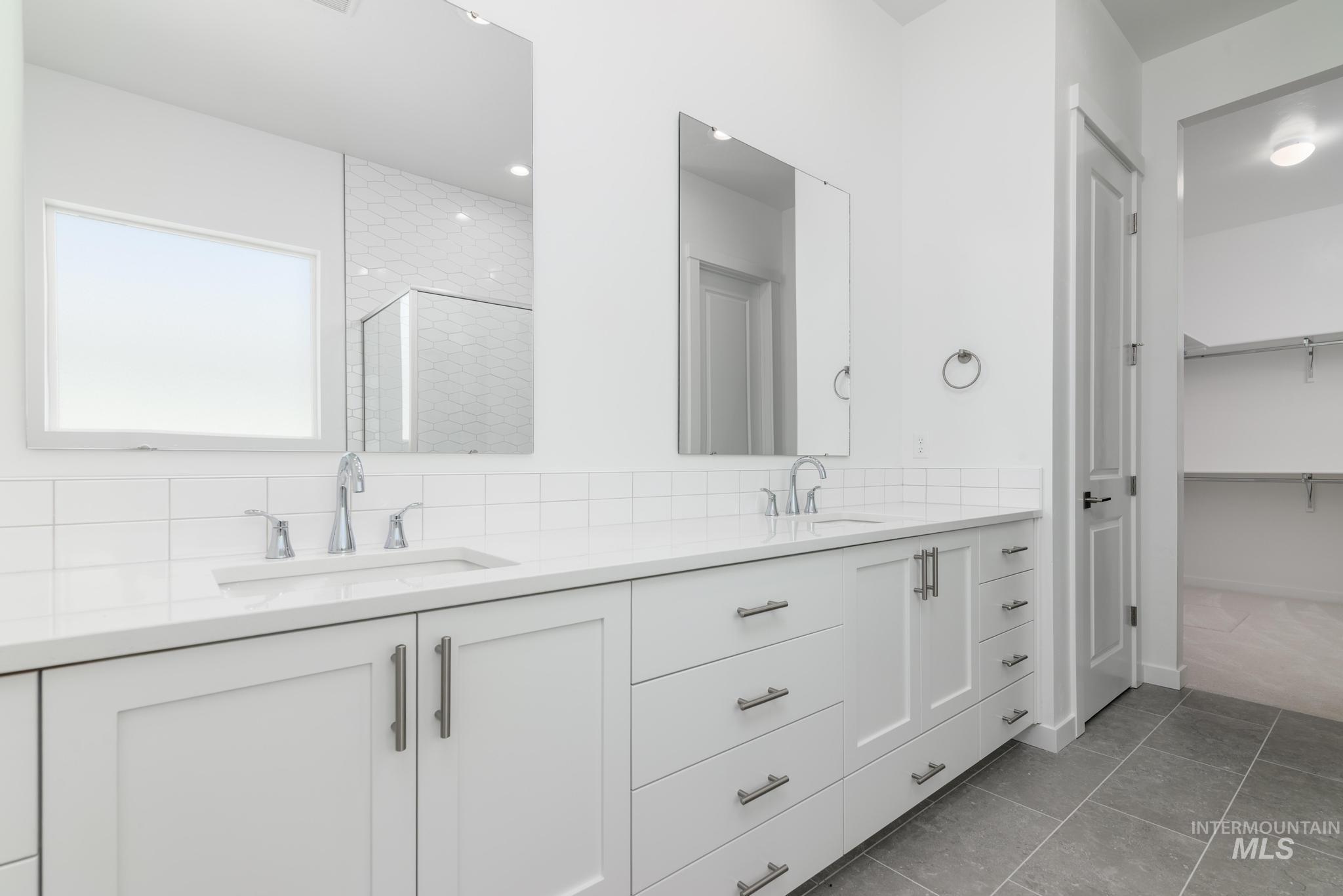 1195 West Switchgrass Drive Meridian, ID 83642 - Photo 8 of 11 Full bathroom with a stall shower, double vanity, light tile patterned floors, a spacious closet, and backsplash