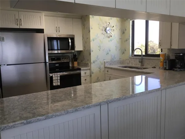 a kitchen with stainless steel appliances granite countertop a refrigerator a stove and a sink