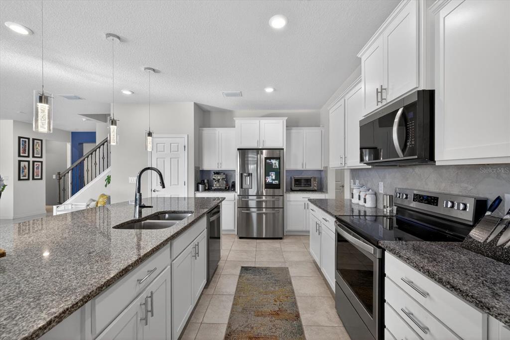 12740 Palapa Loop Spring Hill, FL 34610 - Photo 24 of 68 a large kitchen with stainless steel appliances granite countertop a stove a sink dishwasher a microwave oven with granite countertops and cabinets