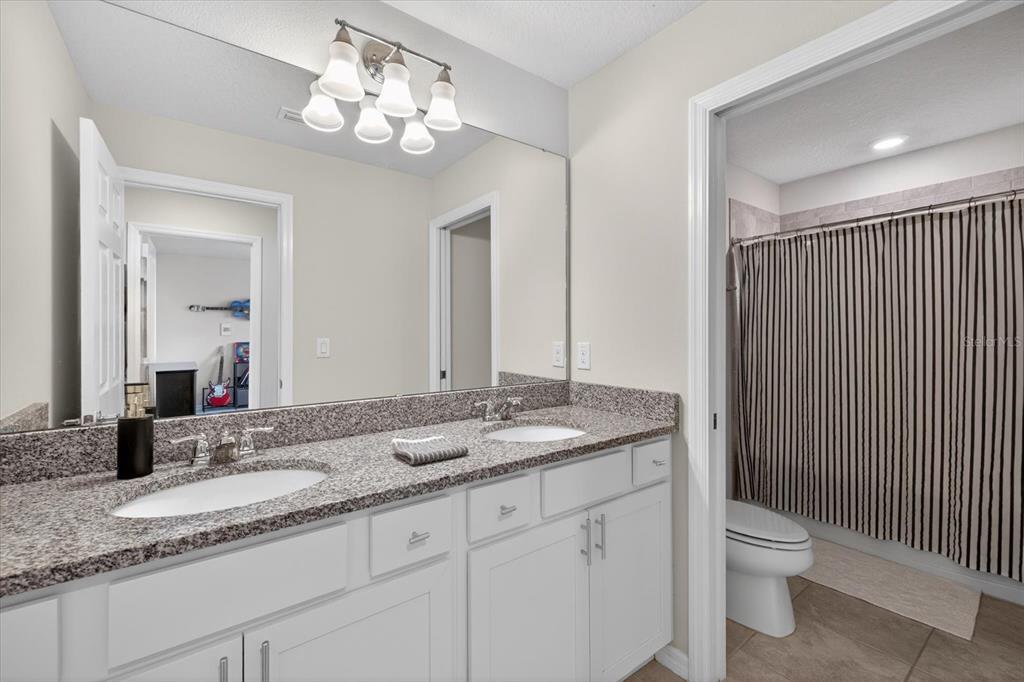 12740 Palapa Loop Spring Hill, FL 34610 - Photo 35 of 68 a bathroom with a granite countertop sink a toilet and a mirror