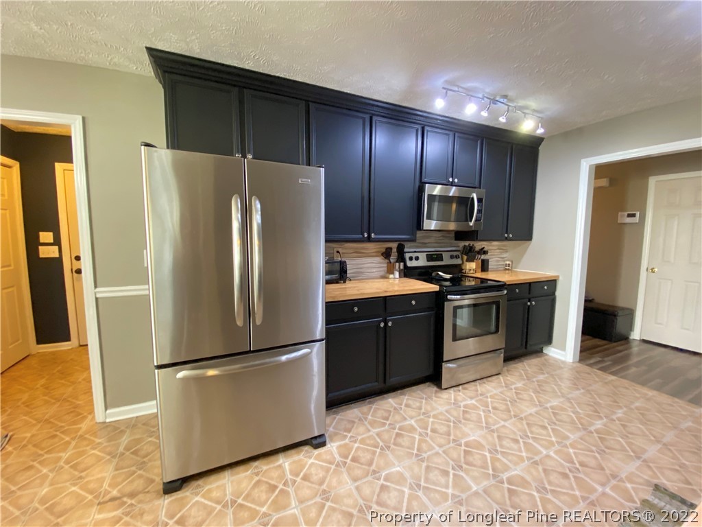 271 Stone Cross Drive Spring Lake, NC 28390 - Photo 11 of 38 a kitchen with granite countertop wooden cabinets a refrigerator and a stove top oven