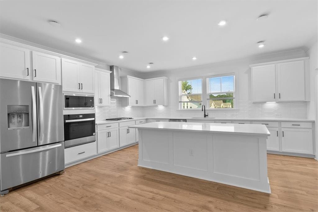 3376 Macaiva Alley Avondale Estates, GA 30002 - Photo 7 of 42 a modern kitchen with stainless steel appliances granite countertop a stove a sink dishwasher a refrigerator and white cabinets with wooden floor