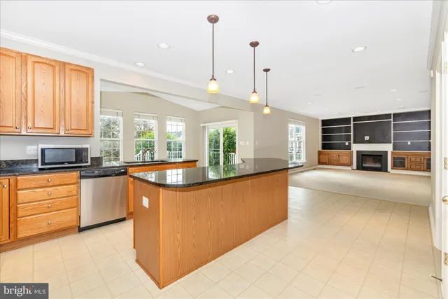 a large kitchen with stainless steel appliances granite countertop a sink a counter space and a window