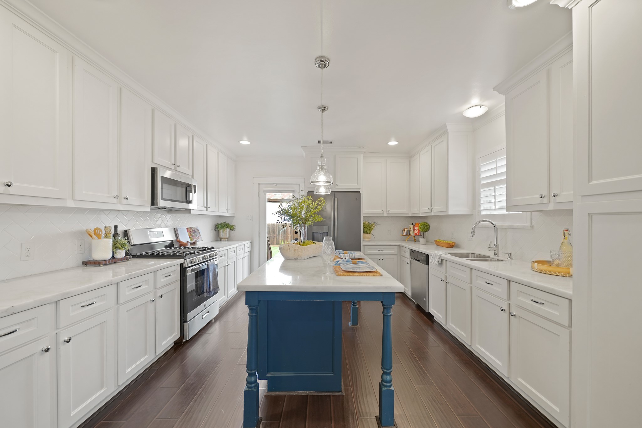 1311 Walton Street Houston, TX 77009 - Photo 13 of 43 This thoughtfully designed kitchen offers a clean and classic look with hardwood floors, marble countertops, herringbone patterned subway tile and shaker-style cabinets with decorative hardware.