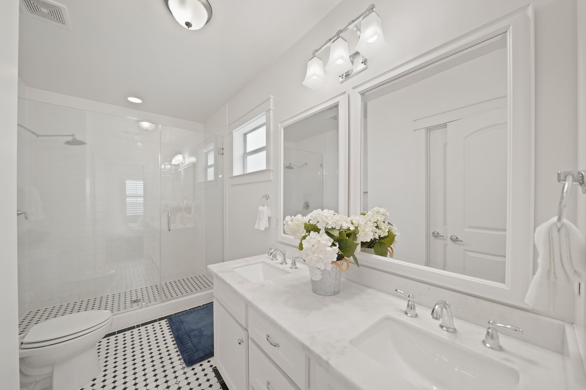 1311 Walton Street Houston, TX 77009 - Photo 22 of 43 The primary bathroom includes decorative tile floors, dual sinks with marble countertops and shaker-style cabinets with chrome hardware. Framed mirrors with lighting above bring a crisp, finished look to the space.