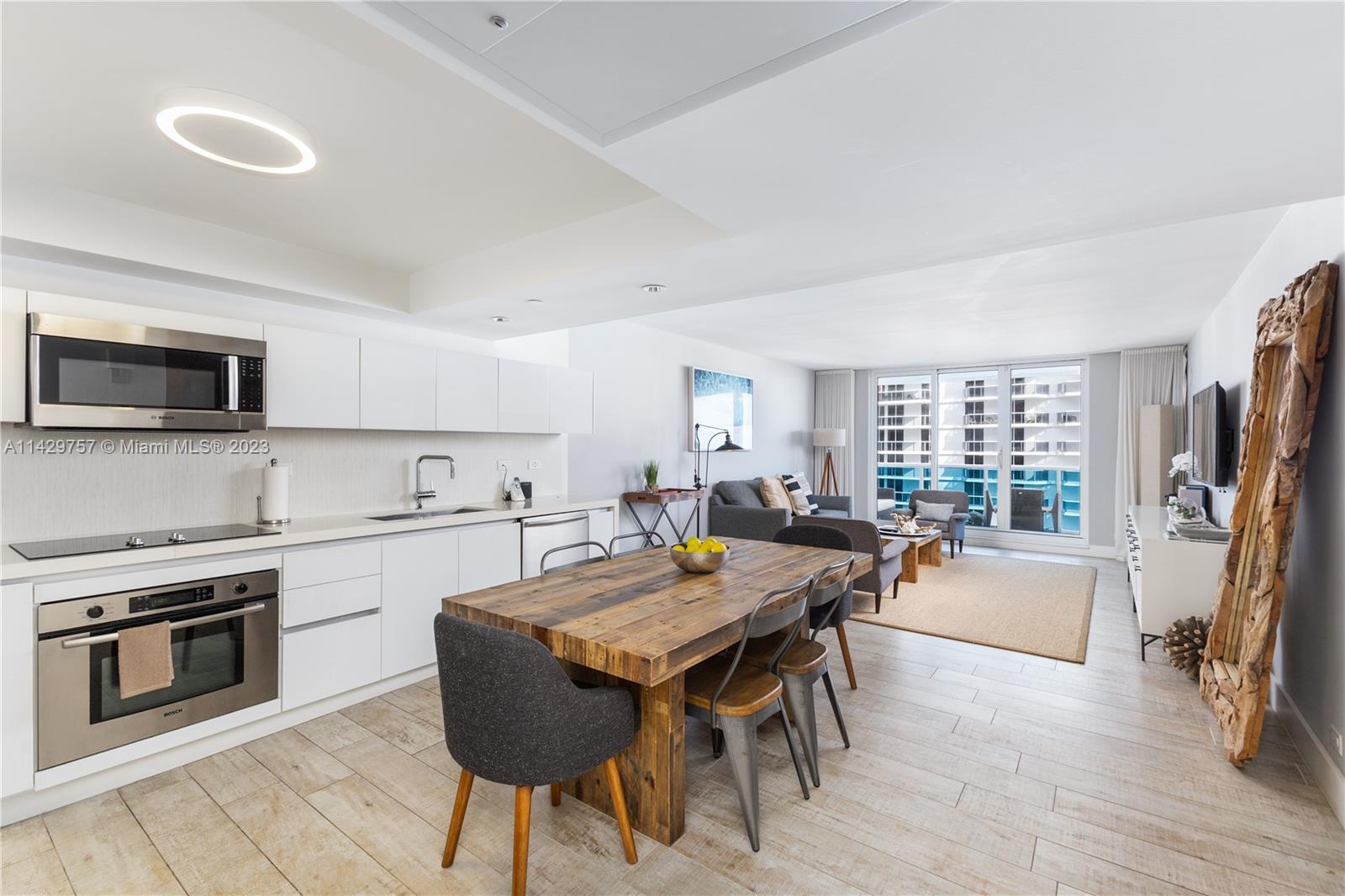 102 24th Street, Unit 1013 Miami Beach, FL 33139 - Photo 19 of 38 a kitchen with a table chairs refrigerator and a stove top oven