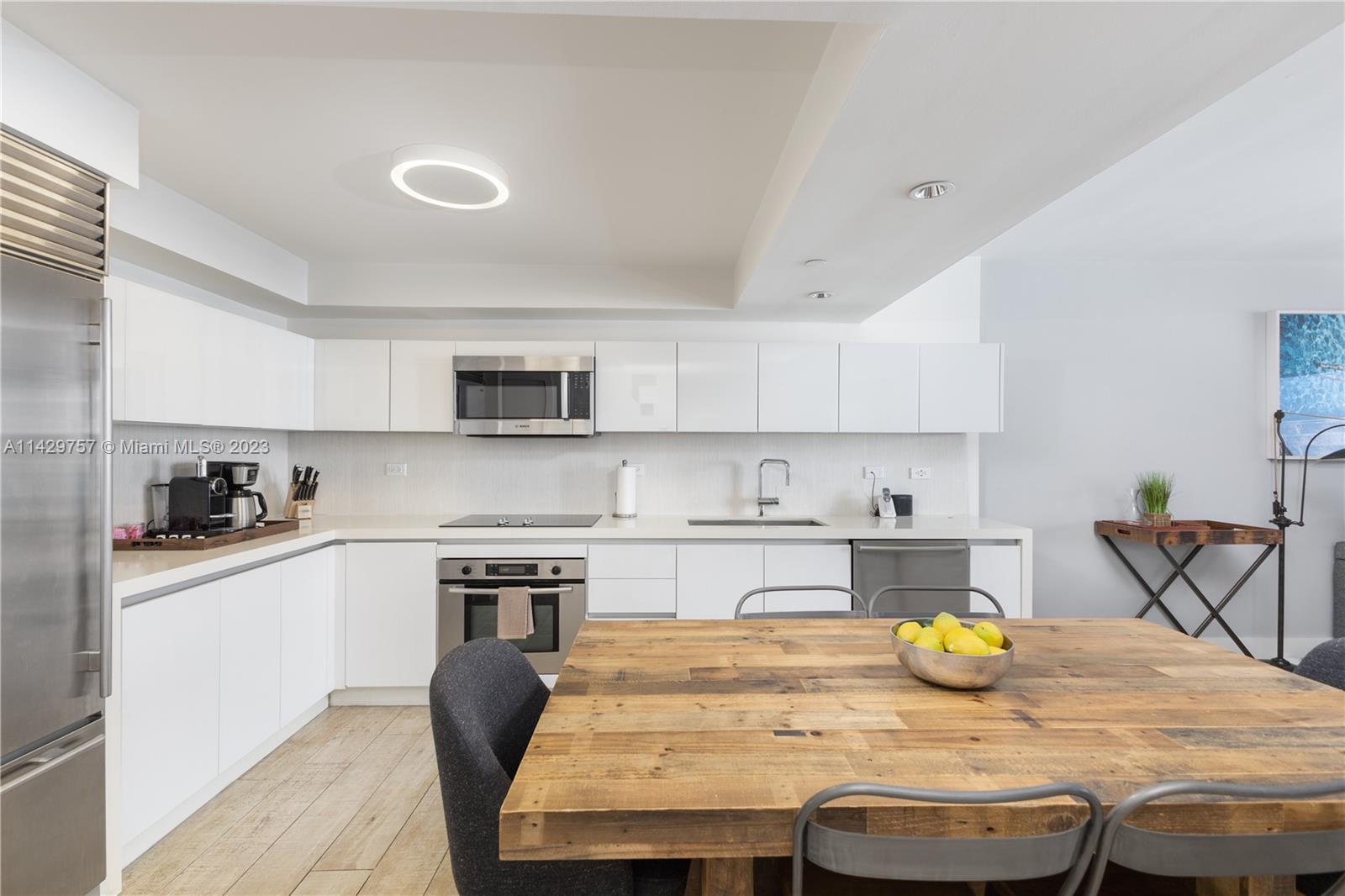 102 24th Street, Unit 1013 Miami Beach, FL 33139 - Photo 25 of 38 a kitchen with stainless steel appliances granite countertop a table chairs sink and cabinets