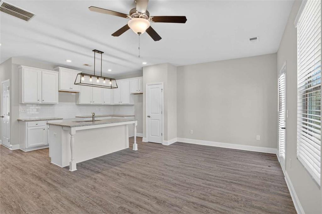 3405 Ripple Loop, Unit 127 South Fulton, GA 30349 - Photo 5 of 26 a kitchen with granite countertop a stove a sink and white cabinets with wooden floor