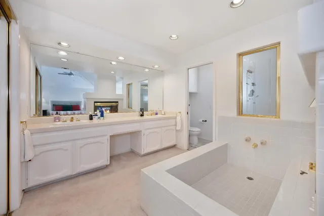 a large white bathroom with a tub a sink and a mirror