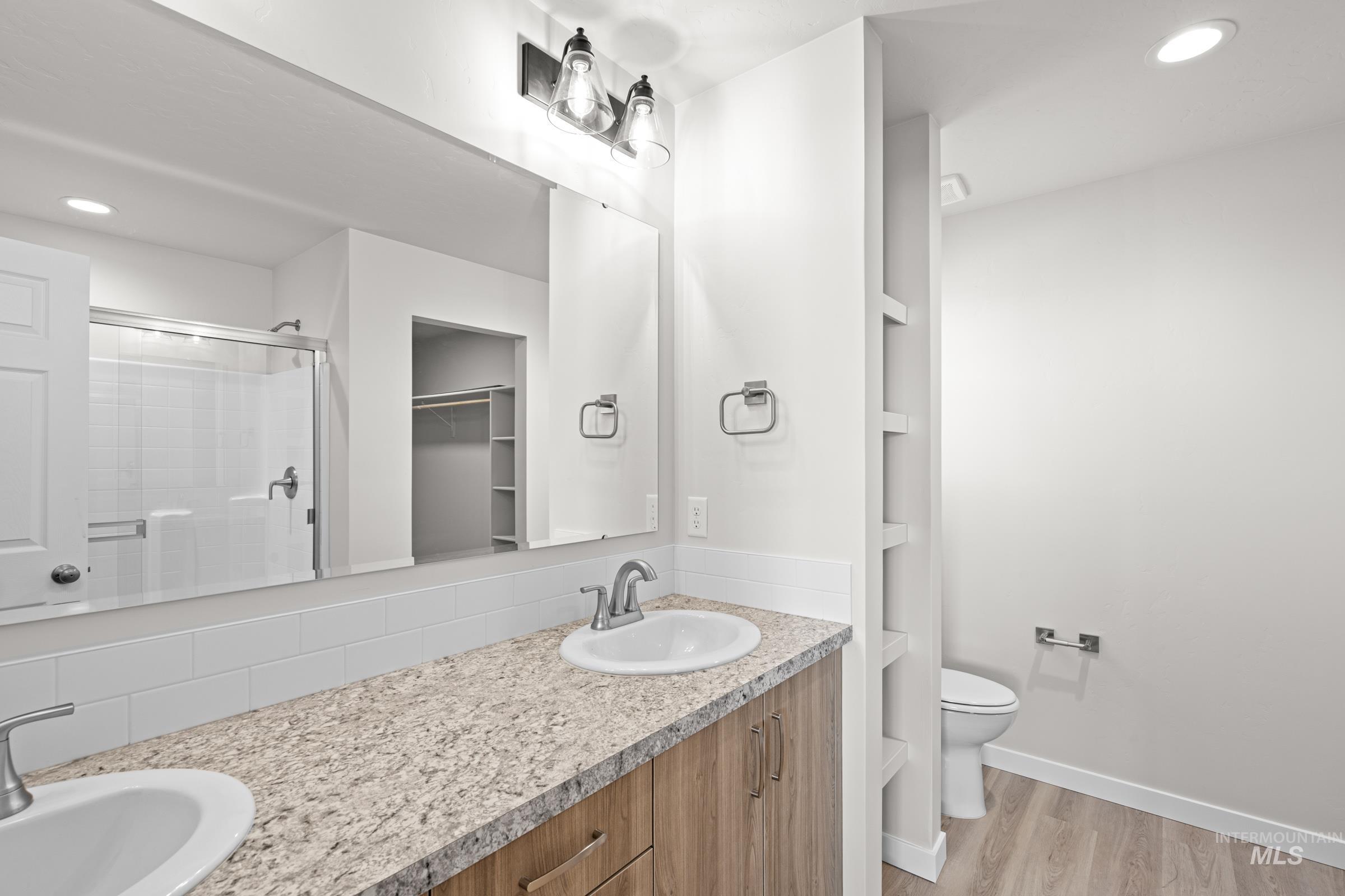 1622 Covington Street Middleton, ID 83644 - Photo 16 of 19 Full bathroom with recessed lighting, double vanity, light wood-type flooring, a shower stall, and a walk in closet