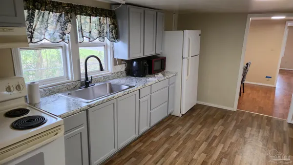 a kitchen with stainless steel appliances a stove a sink a refrigerator and wooden floor