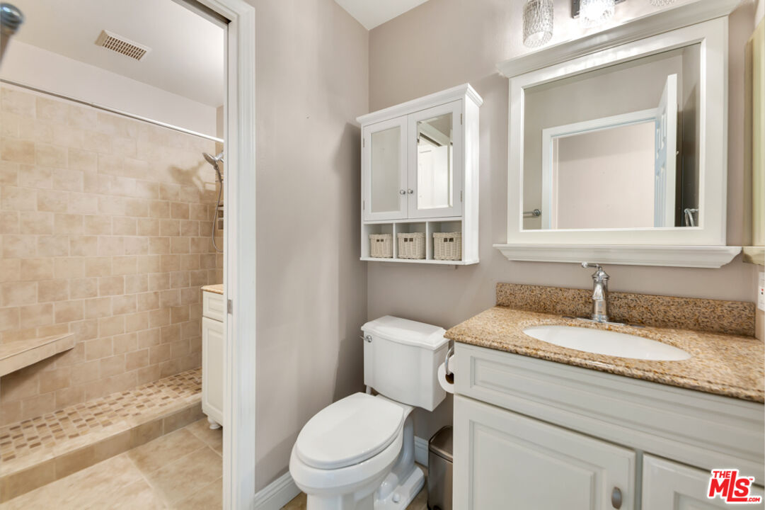 13480 Laurelhurst Road Moorpark, CA 93021 - Photo 14 of 34 a bathroom with a granite countertop toilet a sink and a mirror