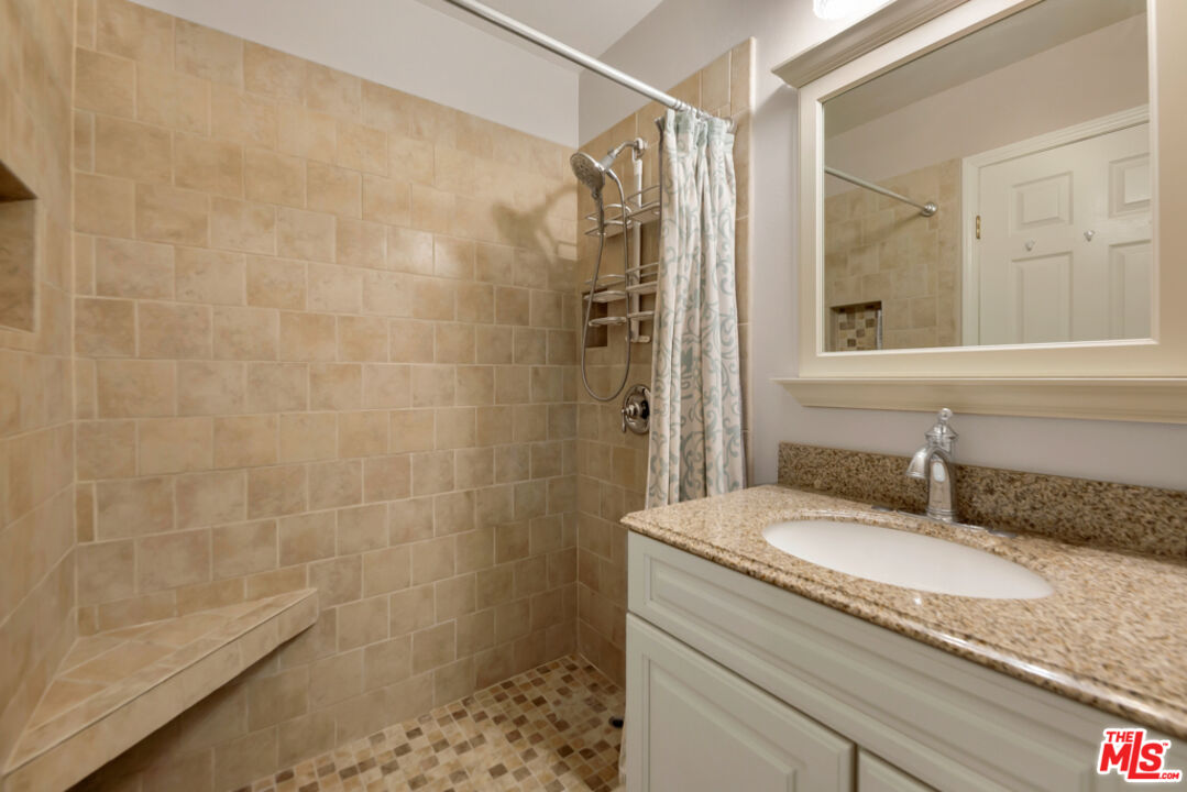 13480 Laurelhurst Road Moorpark, CA 93021 - Photo 15 of 34 a bathroom with a granite countertop sink a mirror and shower