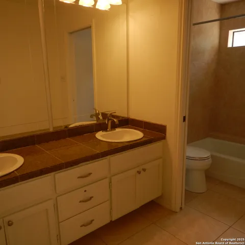 a bathroom with a granite countertop toilet and a sink