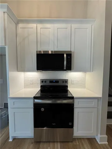a kitchen with white cabinets and black appliances
