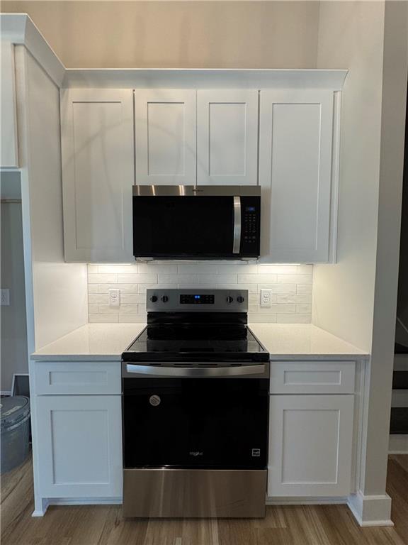 1612 Pickens Street Ball Ground, GA 30107 - Photo 10 of 53 a kitchen with white cabinets and black appliances