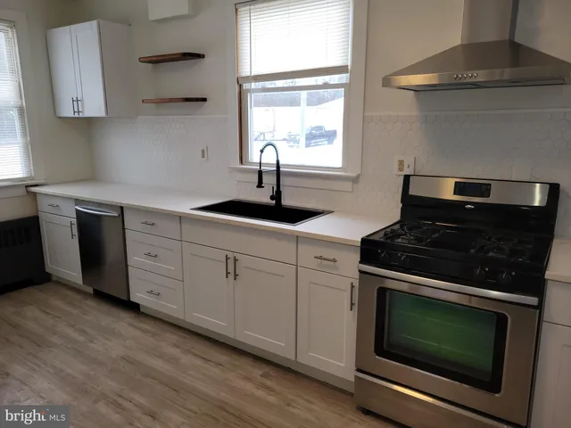 a kitchen with granite countertop white cabinets appliances and a window