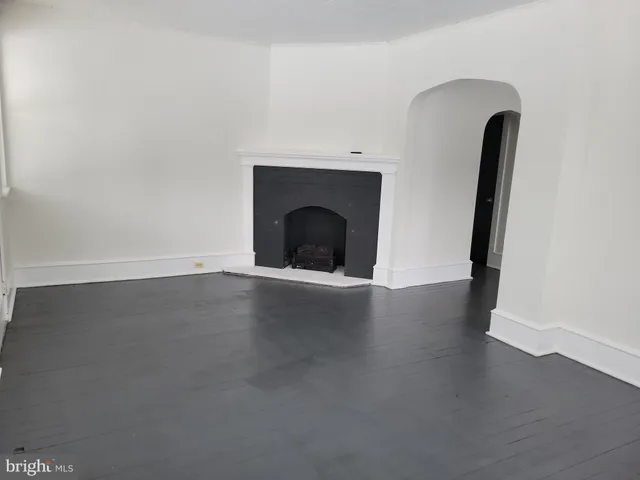 an empty room with wooden floor and fireplace