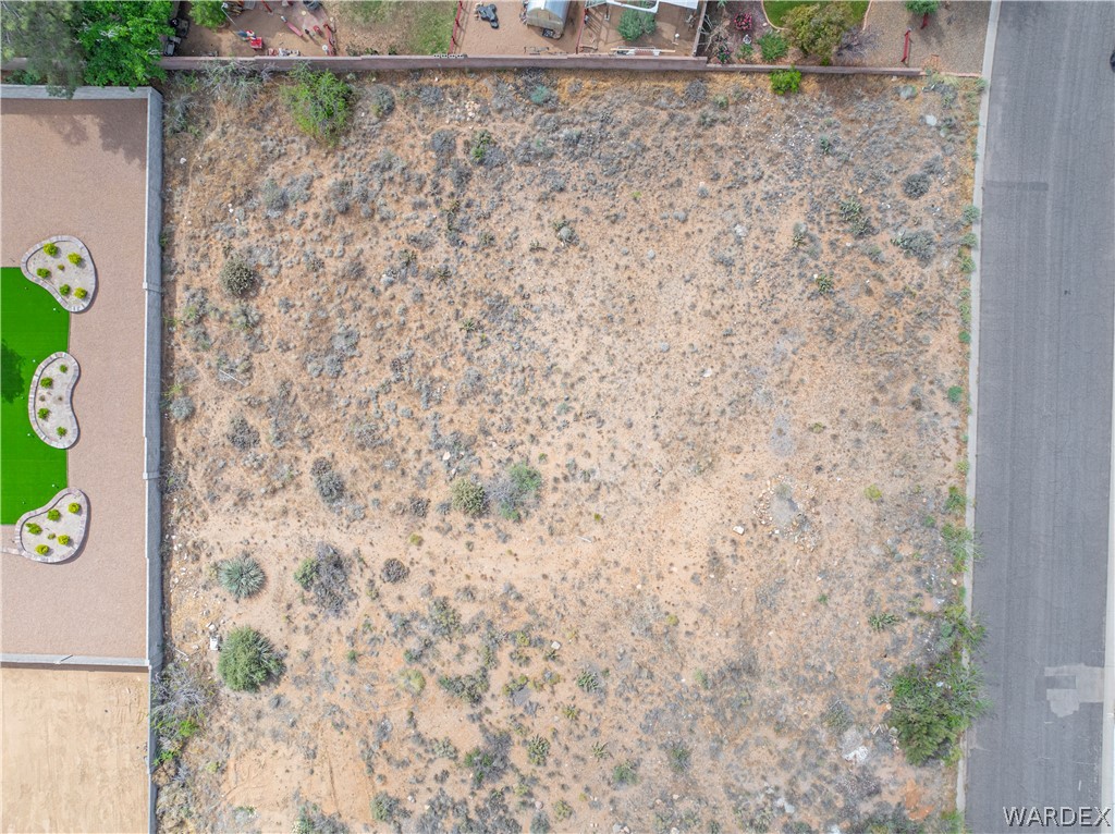1400 Hidden Canyon Road Kingman, AZ 86401 - Photo 3 of 20 Aerial view of the property, featuring an undeveloped lot with sparse vegetation and a paved road bordering one side
