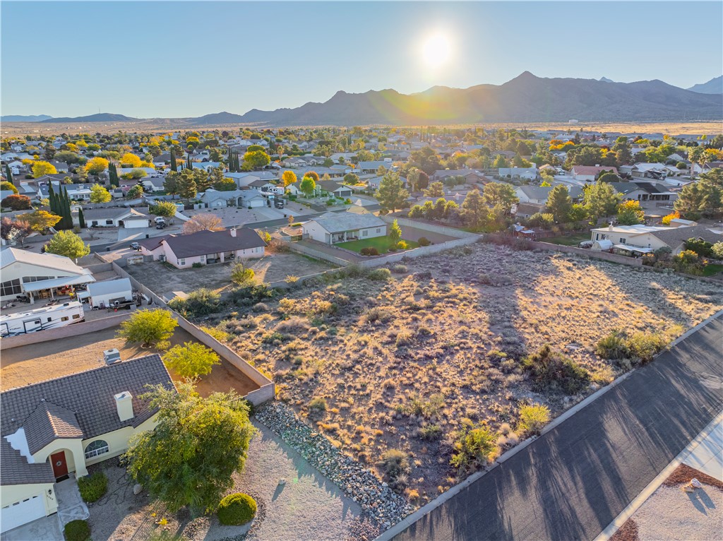1400 Hidden Canyon Road Kingman, AZ 86401 - Photo 6 of 20 Aerial view of a residential area with a prominent, undeveloped lot, surrounded by single-story homes and distant mountains