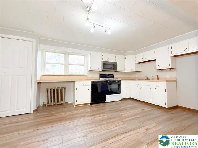 a kitchen with granite countertop white cabinets and wooden floor