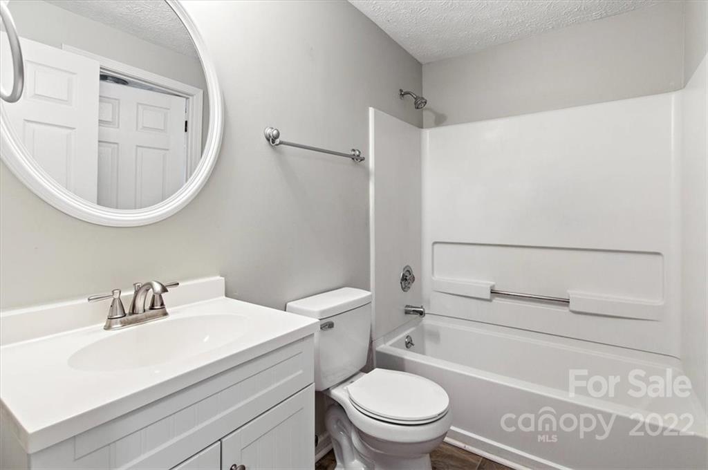 1235 Scaleybark Road, Unit E Charlotte, NC 28209 - Photo 19 of 23 a bathroom with a sink a toilet and a mirror