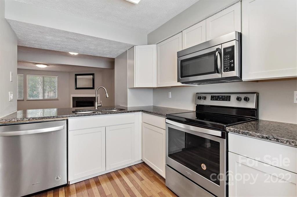 1235 Scaleybark Road, Unit E Charlotte, NC 28209 - Photo 5 of 23 a kitchen with white cabinets and stainless steel appliances
