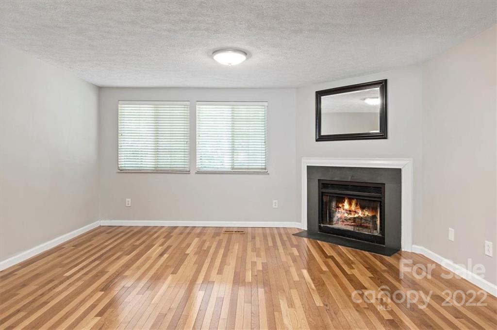 1235 Scaleybark Road, Unit E Charlotte, NC 28209 - Photo 7 of 23 a view of an empty room with wooden floor fireplace and a window