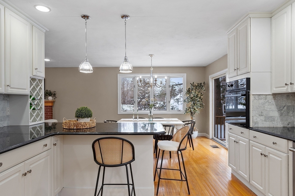 30 Duck Road Reading, MA 01867 - Photo 13 of 42 a kitchen with granite countertop a table chairs stove and white cabinets