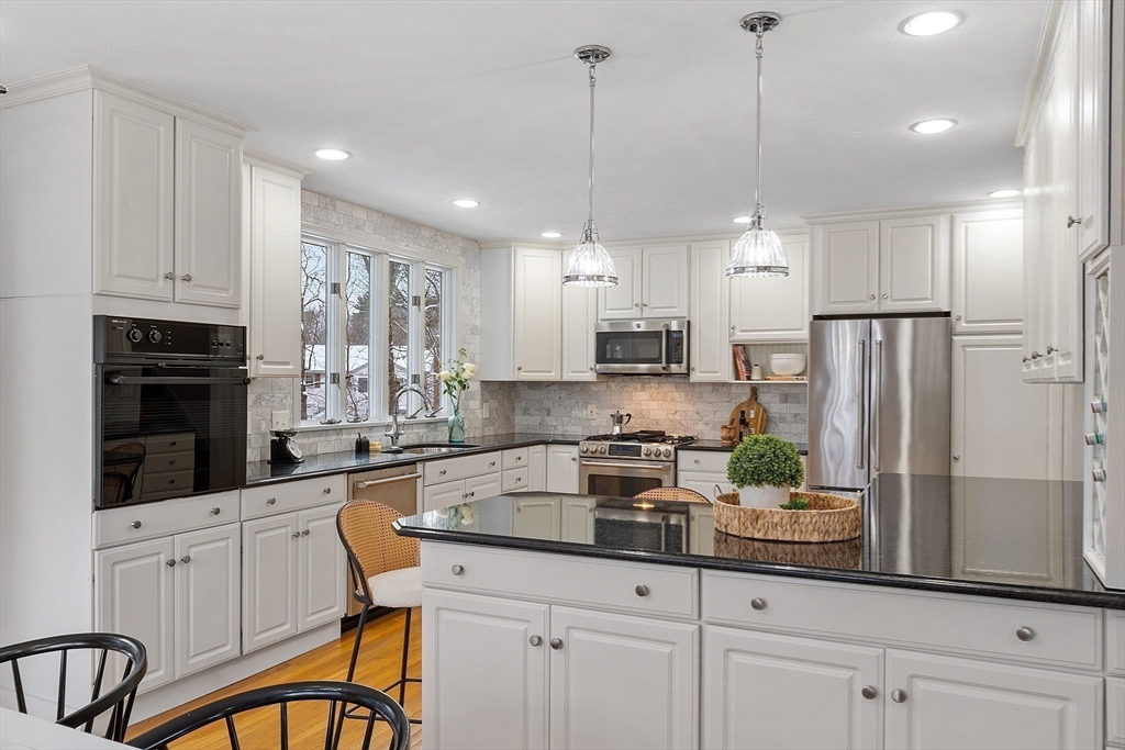 30 Duck Road Reading, MA 01867 - Photo 14 of 42 a kitchen with stainless steel appliances kitchen island granite countertop a refrigerator a stove a sink and white cabinets with wooden floor