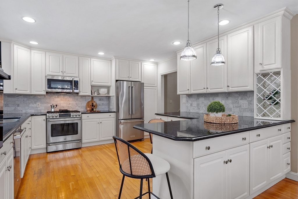 30 Duck Road Reading, MA 01867 - Photo 16 of 42 a kitchen with stainless steel appliances granite countertop a sink a stove a refrigerator cabinets and chairs
