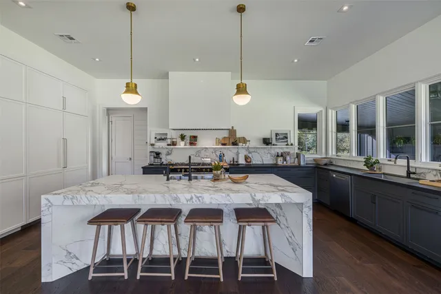 a kitchen with stainless steel appliances kitchen island granite countertop a stove a sink a dining table and chairs with wooden floor