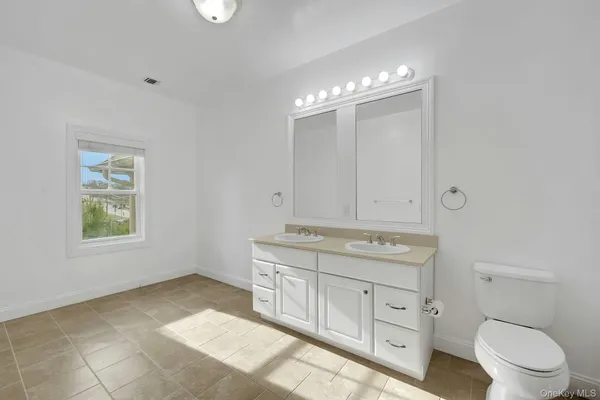 a spacious bathroom with a granite countertop toilet a sink and a mirror