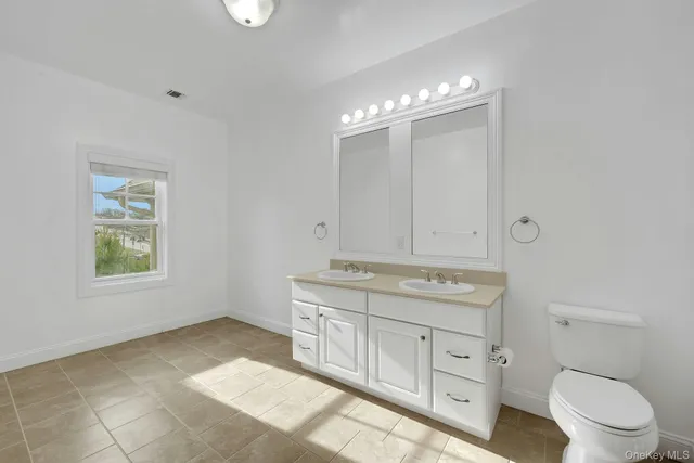 a spacious bathroom with a granite countertop toilet a sink and a mirror