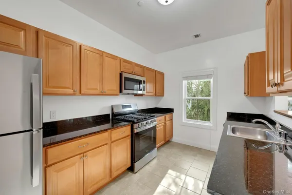 a kitchen with stainless steel appliances granite countertop a stove a sink and a microwave