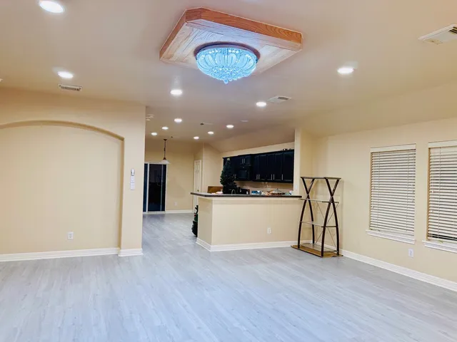 a view of living room with kitchen island stainless steel appliances wooden floor and window