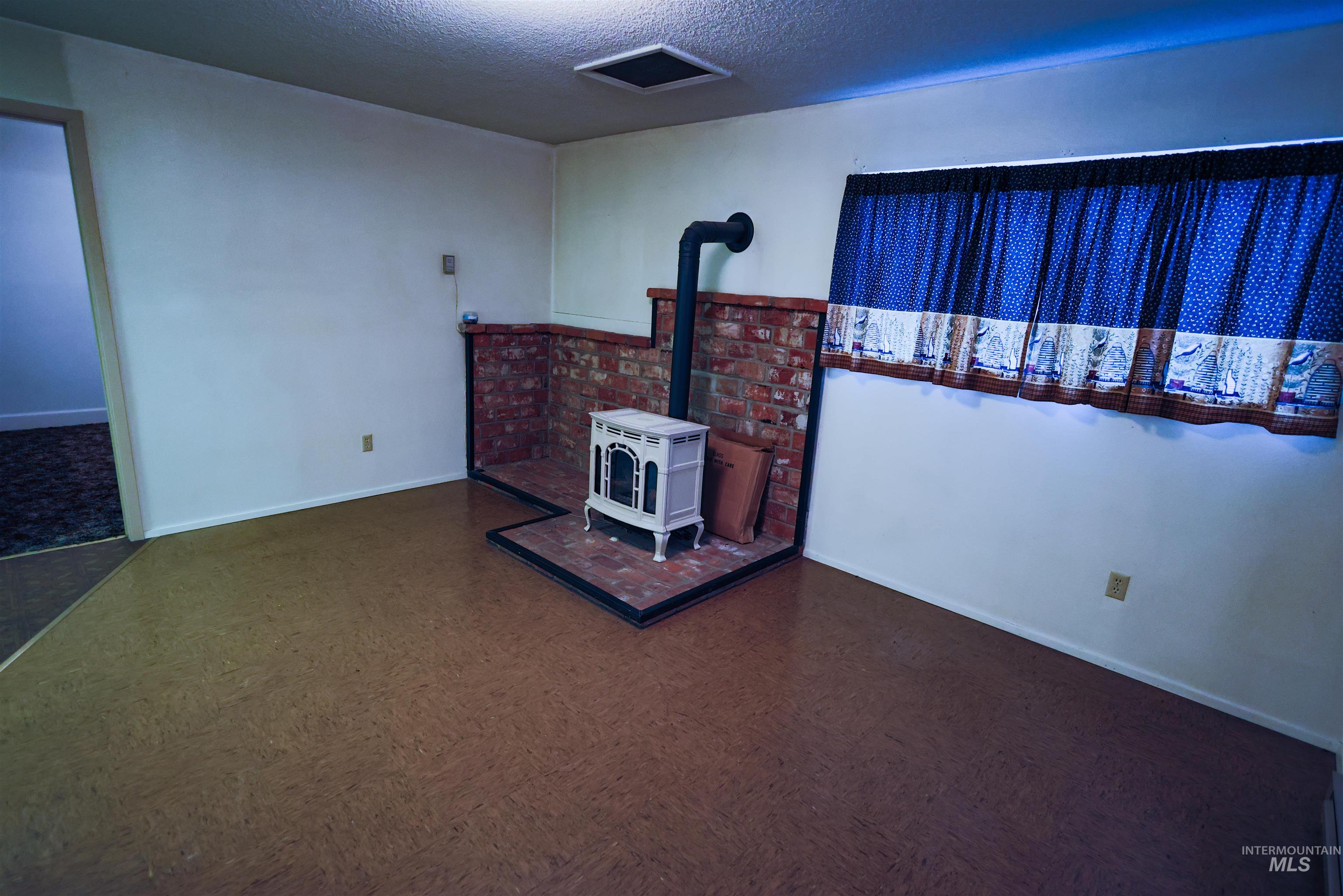 717 Big Cedar Road Kooskia, ID 83539 - Photo 16 of 50 Unfurnished living room with a wood stove, a textured ceiling, and dark flooring