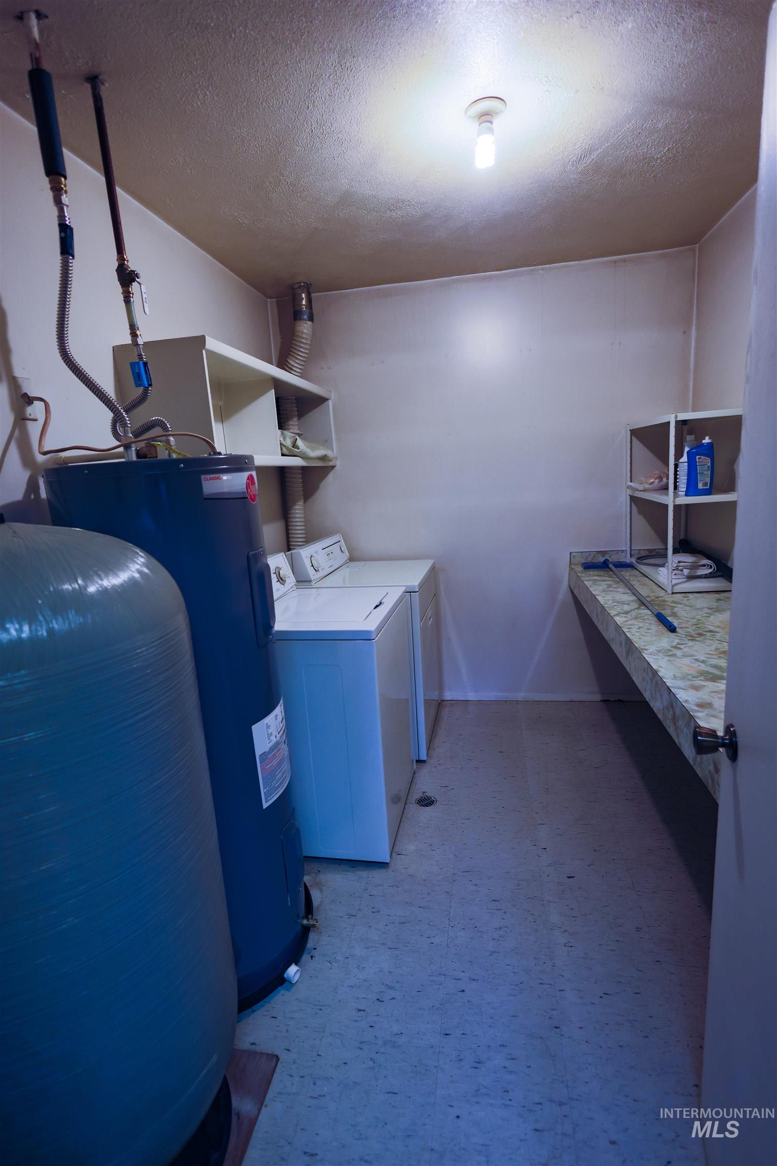 717 Big Cedar Road Kooskia, ID 83539 - Photo 18 of 50 Laundry room featuring light floors, a textured ceiling, washing machine and dryer, and electric water heater