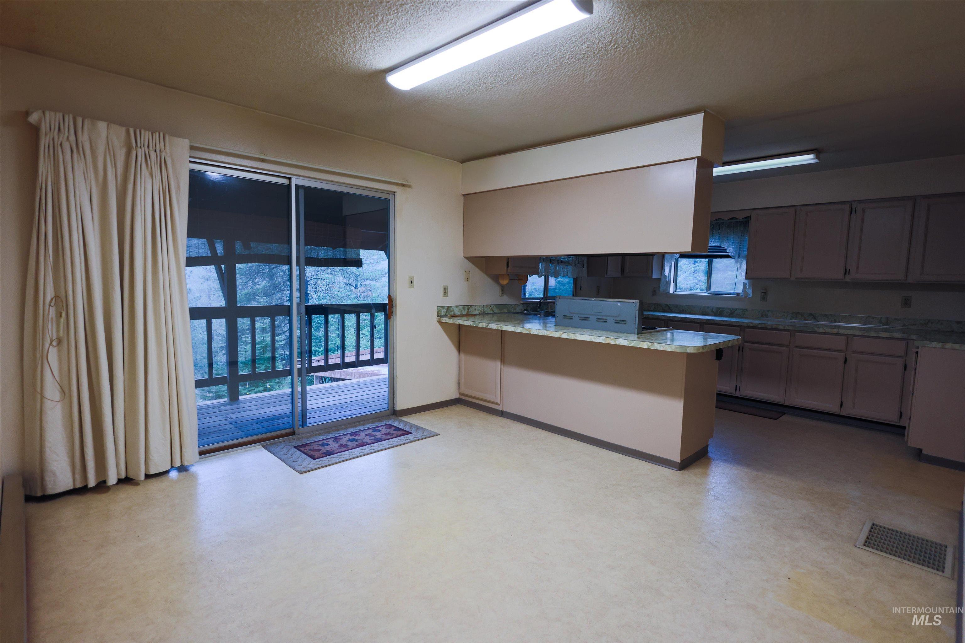 717 Big Cedar Road Kooskia, ID 83539 - Photo 2 of 50 Kitchen with light flooring, a textured ceiling, a peninsula, and light stone countertops